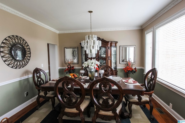 dining room with ornamental molding, a notable chandelier, and hardwood / wood-style floors