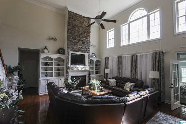 living area with plenty of natural light, dark wood-style floors, ornamental molding, and a ceiling fan
