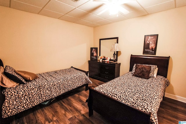 bedroom with a paneled ceiling, dark hardwood / wood-style flooring, and ceiling fan