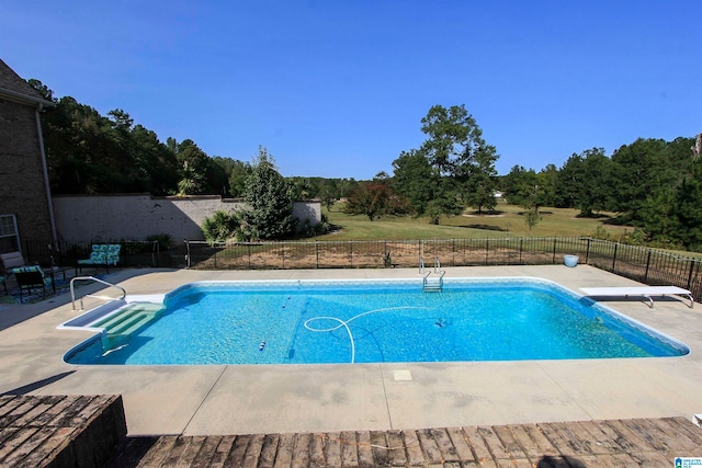 view of pool with a diving board and a patio area