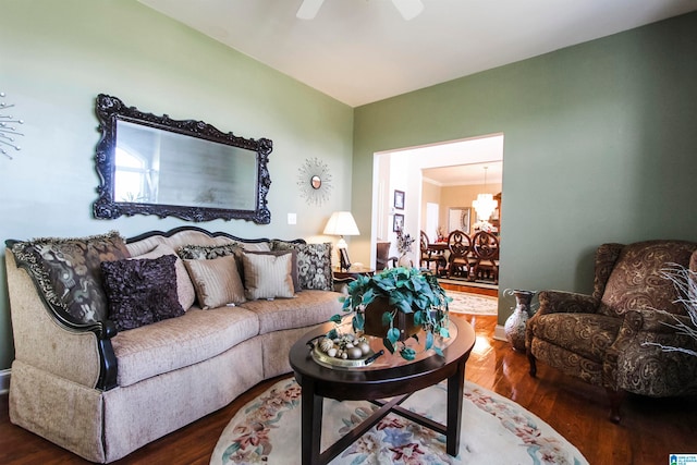 living room featuring wood-type flooring, ceiling fan with notable chandelier, and crown molding