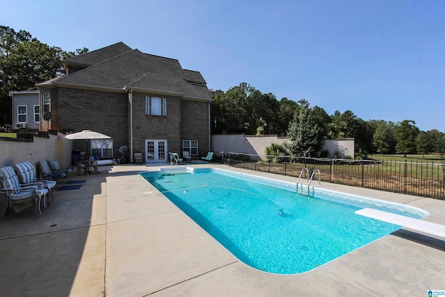 view of swimming pool featuring french doors, a diving board, and a patio