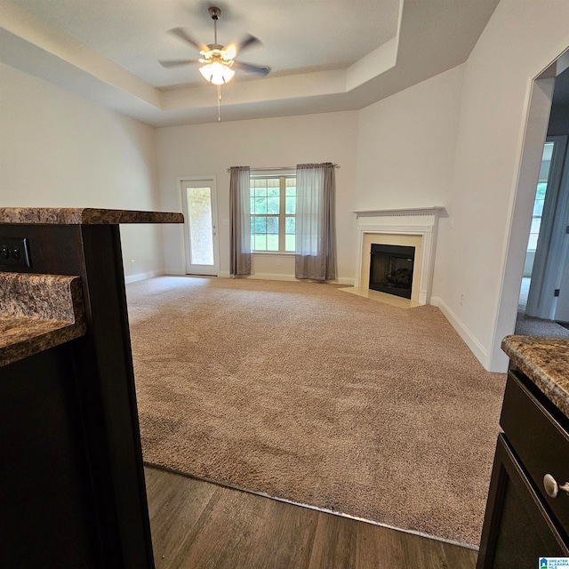 living room featuring wood-type flooring, a raised ceiling, and ceiling fan