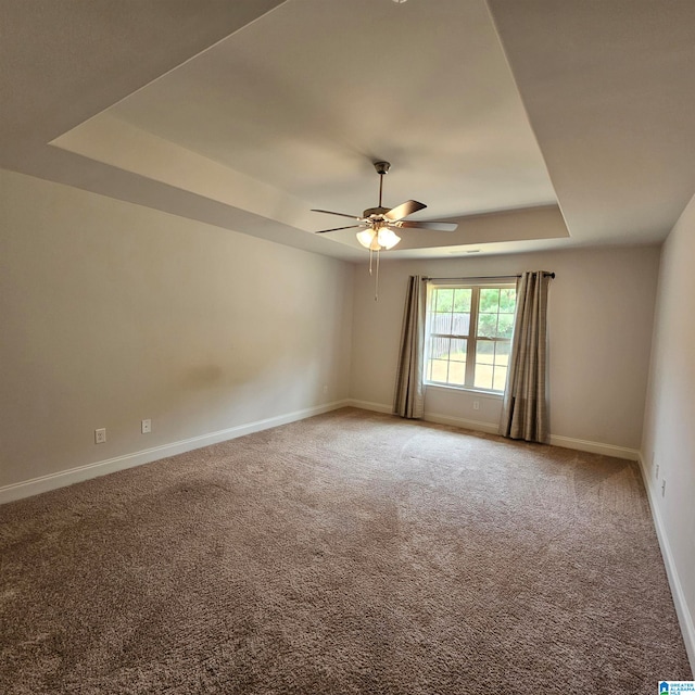 carpeted spare room featuring ceiling fan and a raised ceiling