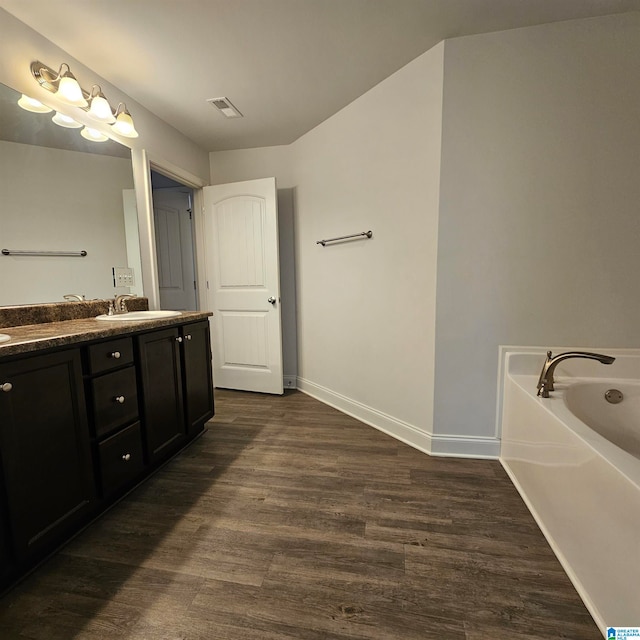 bathroom with wood-type flooring, vanity, and a washtub