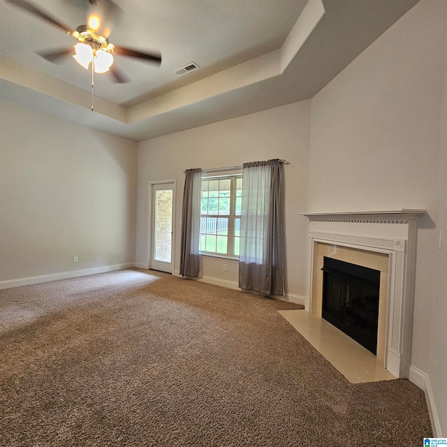 unfurnished living room featuring carpet, a tray ceiling, and ceiling fan