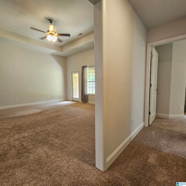 unfurnished room featuring carpet floors, a tray ceiling, and ceiling fan