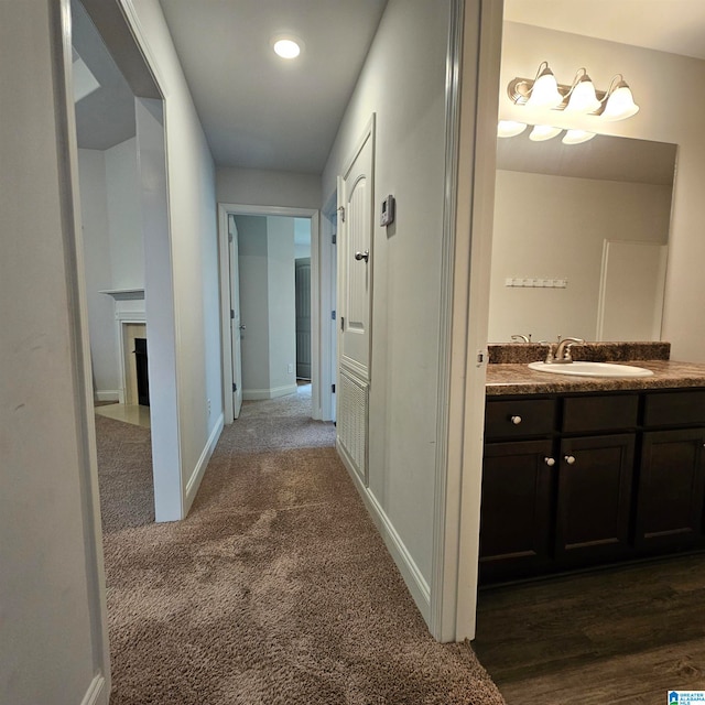 hallway with dark colored carpet and sink