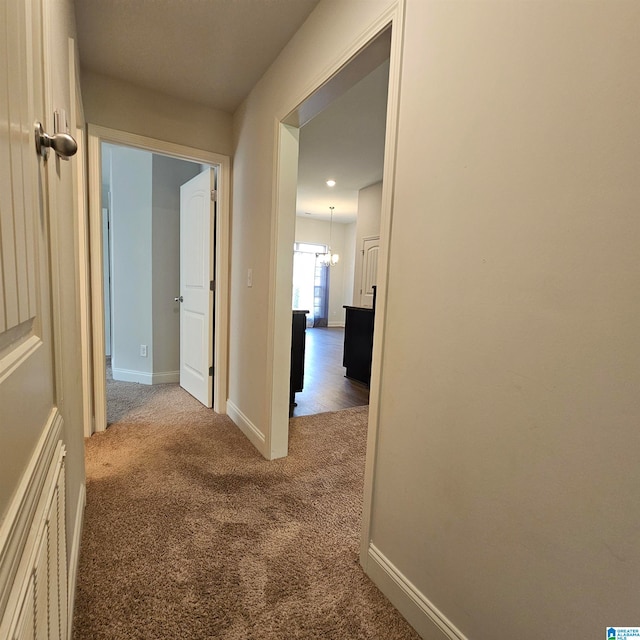 hall with an inviting chandelier and carpet floors