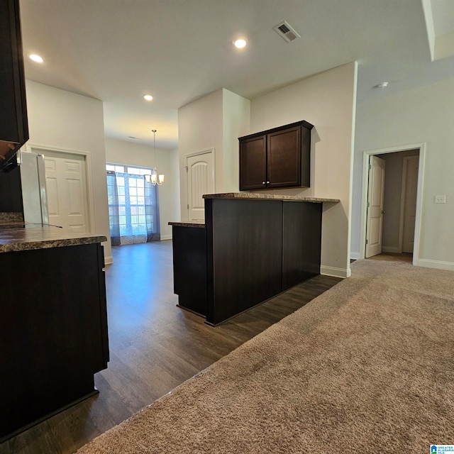 kitchen featuring hanging light fixtures, kitchen peninsula, dark brown cabinets, a chandelier, and dark wood-type flooring