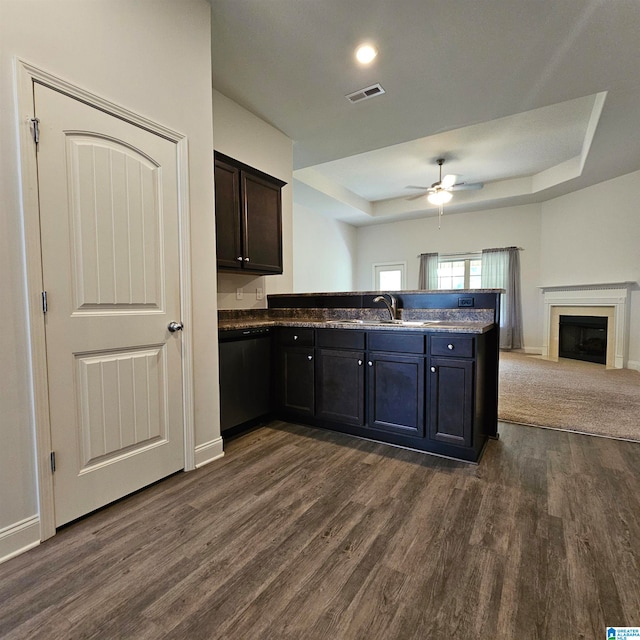 kitchen with dishwasher, a tray ceiling, dark hardwood / wood-style floors, sink, and ceiling fan