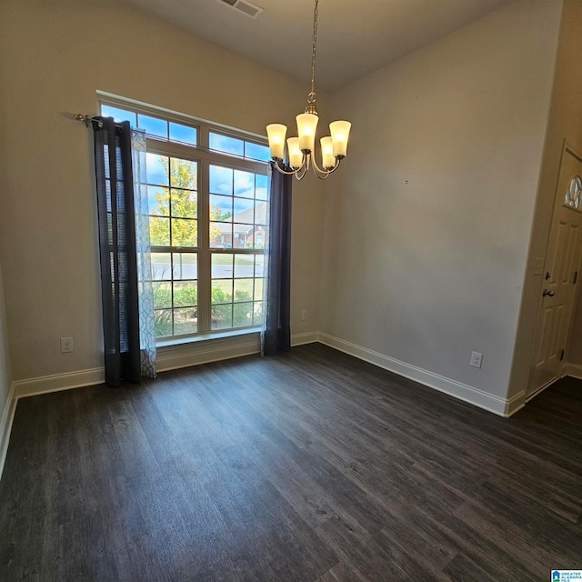 spare room with an inviting chandelier and dark hardwood / wood-style flooring