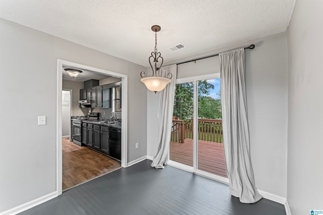 unfurnished dining area with a textured ceiling, sink, and dark wood-type flooring