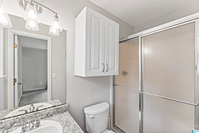 bathroom with a textured ceiling, vanity, toilet, and an enclosed shower