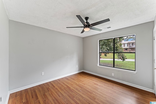 empty room with a textured ceiling, ceiling fan, and hardwood / wood-style flooring