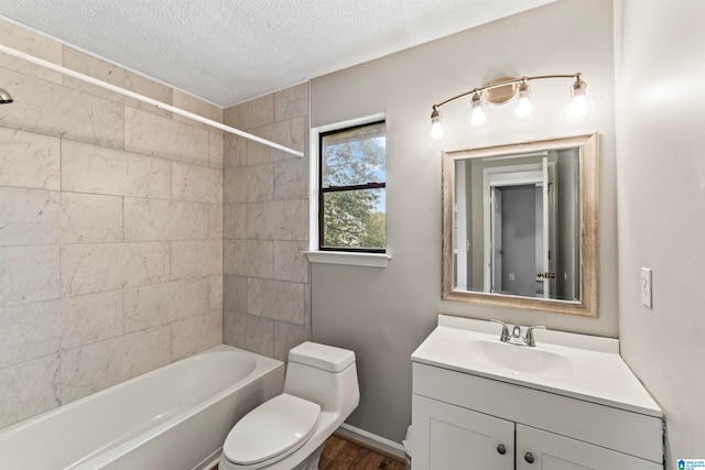 full bathroom with a textured ceiling, hardwood / wood-style floors, tiled shower / bath, vanity, and toilet