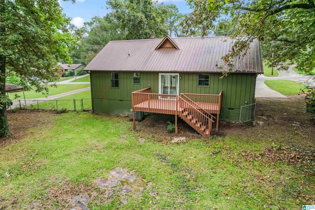 rear view of house with central AC unit and a lawn