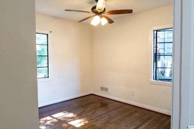 empty room featuring a healthy amount of sunlight, ceiling fan, and dark wood-type flooring