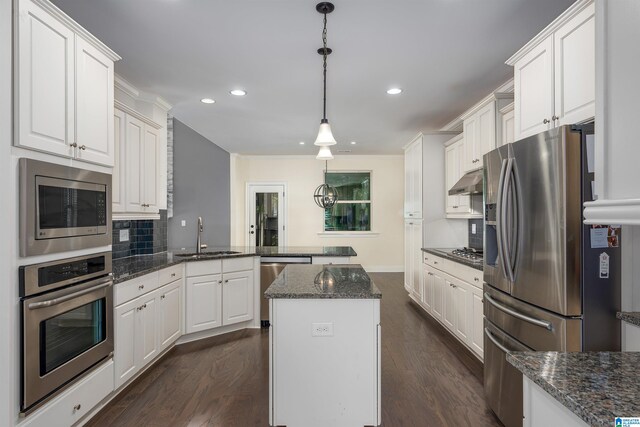 kitchen featuring appliances with stainless steel finishes, dark hardwood / wood-style flooring, sink, decorative light fixtures, and white cabinets