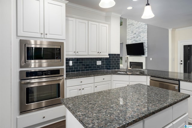 kitchen featuring white cabinets, sink, ornamental molding, decorative light fixtures, and stainless steel appliances