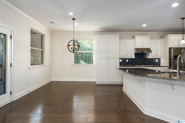 kitchen featuring a kitchen bar, dark stone counters, dark wood-type flooring, decorative light fixtures, and white cabinetry