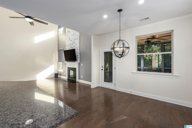 unfurnished living room with a large fireplace, dark hardwood / wood-style flooring, ornamental molding, and a chandelier