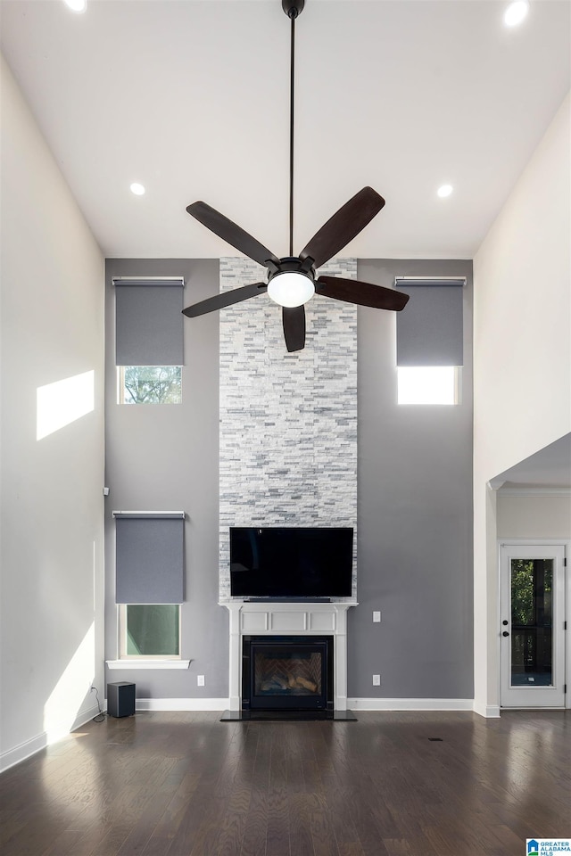 unfurnished living room with a wealth of natural light, a fireplace, ceiling fan, and wood-type flooring