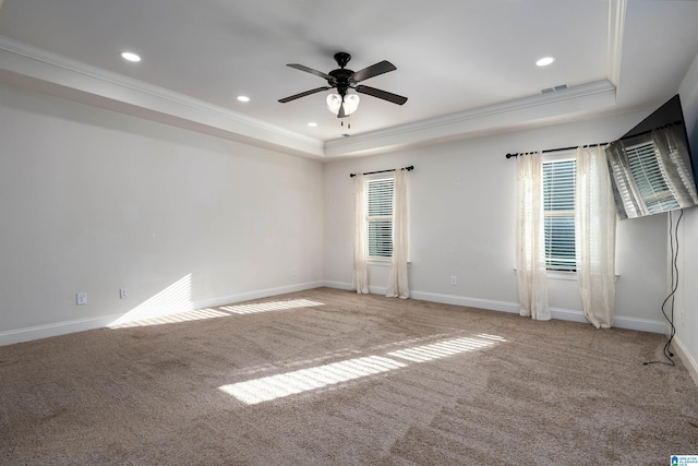 empty room featuring light carpet, a tray ceiling, ceiling fan, and crown molding