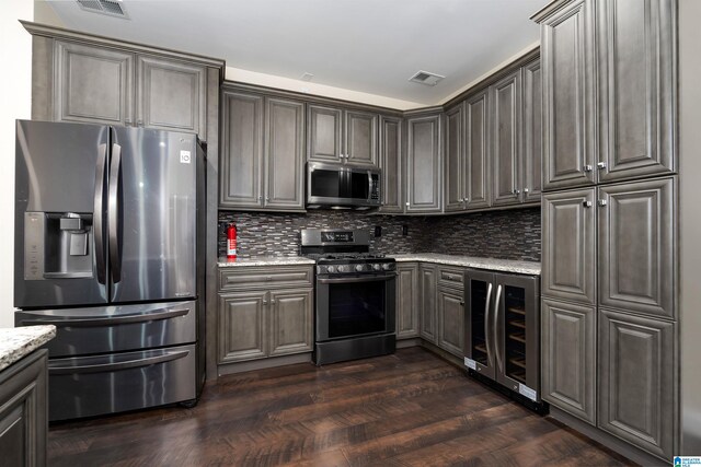 kitchen with stainless steel appliances, wine cooler, light stone counters, dark hardwood / wood-style flooring, and decorative backsplash