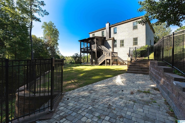 rear view of property with a lawn, a patio, and a wooden deck