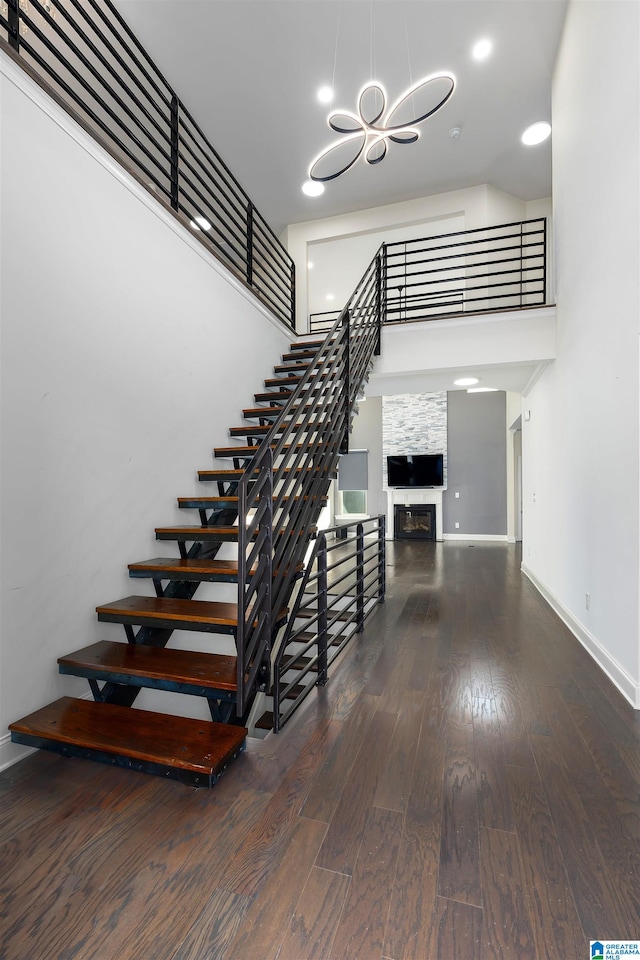 stairway featuring a notable chandelier, wood-type flooring, and a fireplace