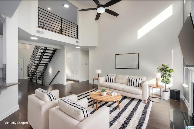 living room featuring ceiling fan, a towering ceiling, and dark hardwood / wood-style floors