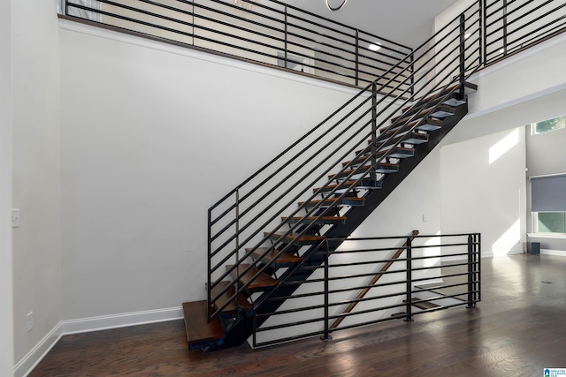 stairs with a high ceiling, a healthy amount of sunlight, and wood-type flooring