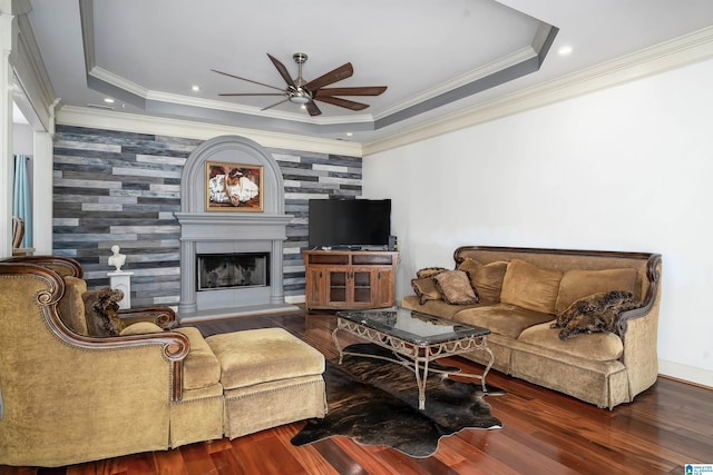 living room with ceiling fan, a raised ceiling, hardwood / wood-style flooring, and crown molding