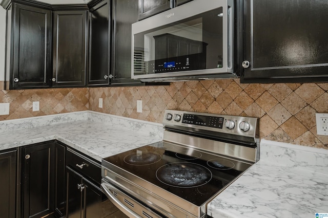 kitchen with light stone counters, backsplash, and appliances with stainless steel finishes