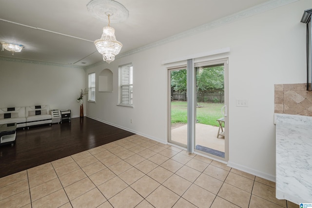 tiled spare room featuring ornamental molding and a chandelier