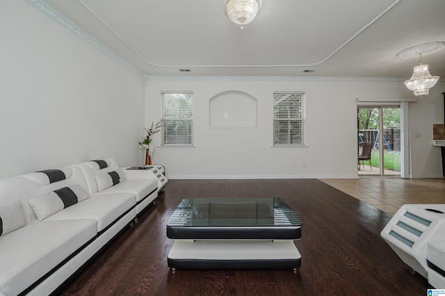 living room with crown molding, a chandelier, and dark wood-type flooring