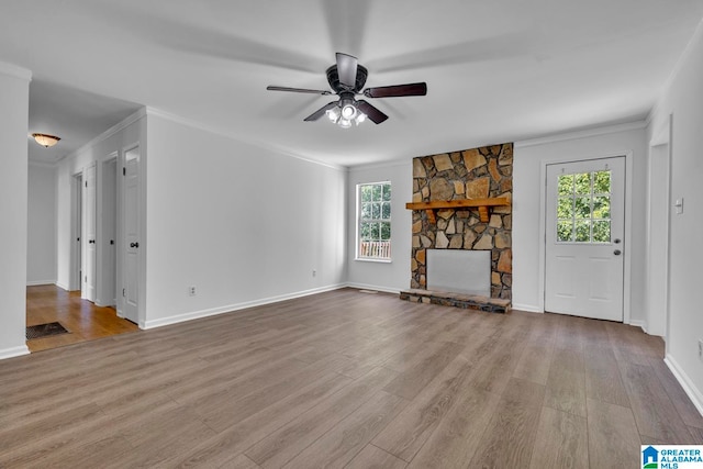 unfurnished living room with a stone fireplace, a wealth of natural light, and light hardwood / wood-style flooring