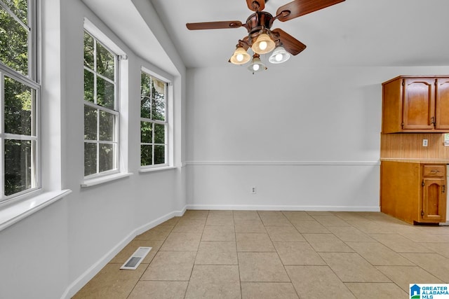 unfurnished dining area with ceiling fan, light tile patterned floors, and vaulted ceiling