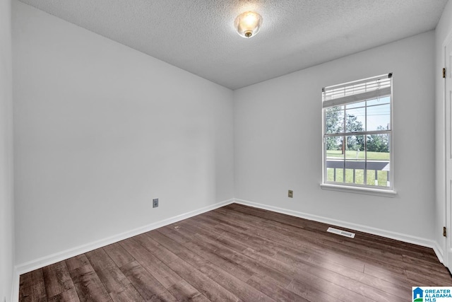 spare room featuring a textured ceiling and dark wood-type flooring