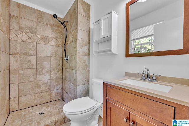 bathroom with a tile shower, vanity, and toilet