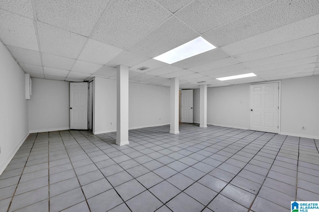 basement featuring a paneled ceiling and light tile patterned floors