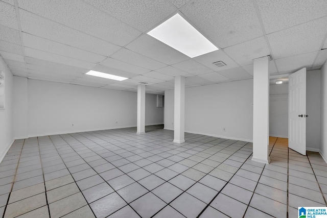 basement featuring a drop ceiling and light tile patterned flooring