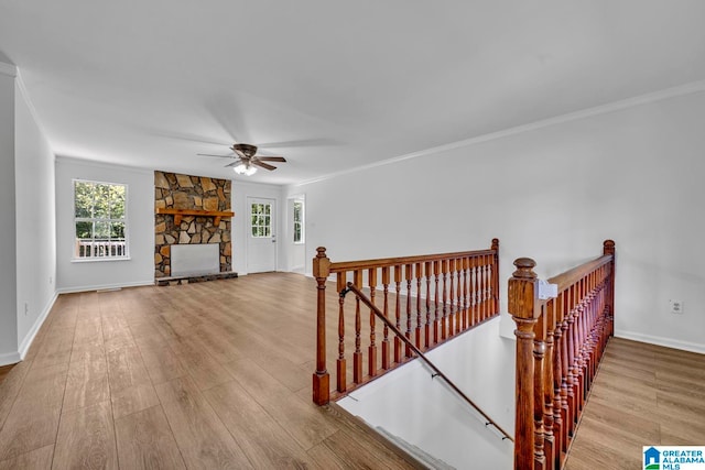 interior space featuring crown molding, a fireplace, ceiling fan, and light wood-type flooring