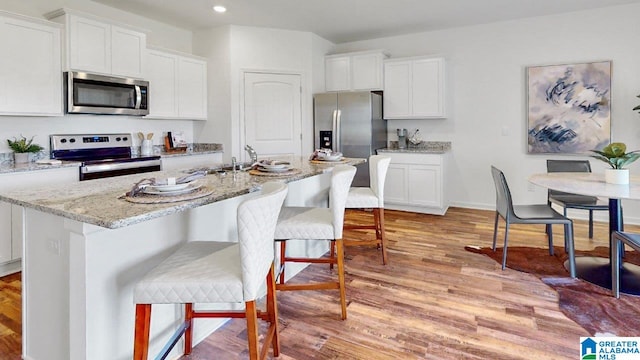 kitchen featuring white cabinets, a center island with sink, and stainless steel appliances