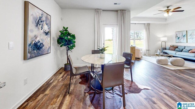 dining room featuring dark hardwood / wood-style flooring, ceiling fan, and a raised ceiling