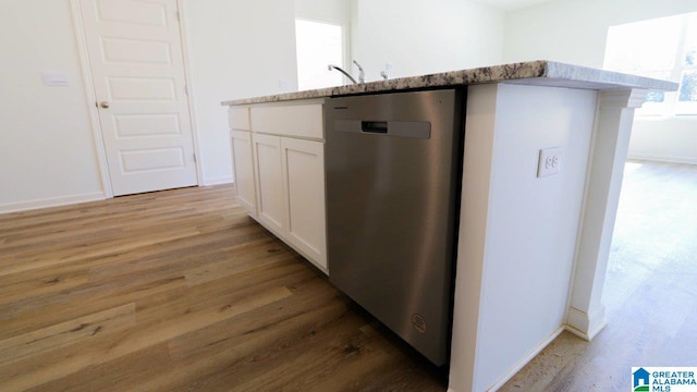 kitchen with light stone countertops, sink, stainless steel dishwasher, hardwood / wood-style floors, and white cabinets