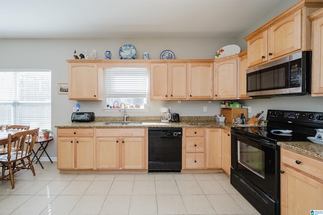 kitchen featuring black appliances, a healthy amount of sunlight, light stone counters, and sink