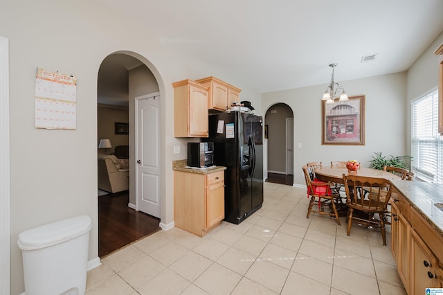 kitchen with black fridge with ice dispenser, light brown cabinets, light tile patterned floors, decorative light fixtures, and a notable chandelier