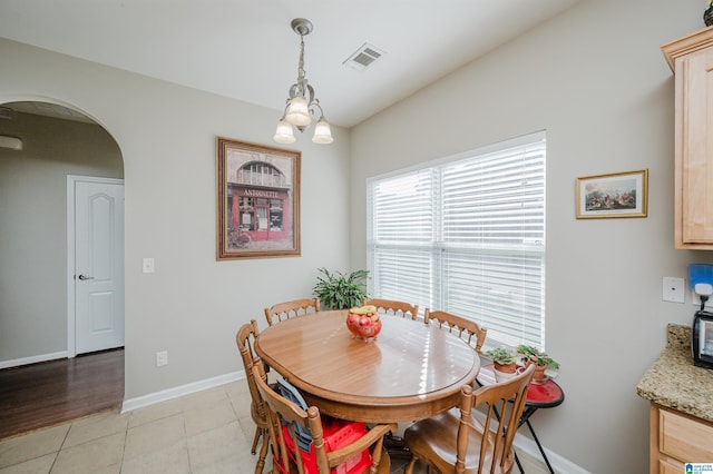 dining space featuring light tile patterned floors and a notable chandelier